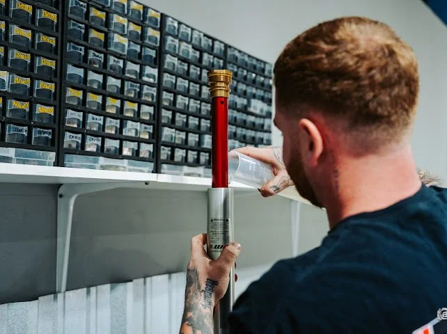 A tech fills a fork leg at M2R Offroad Suspension