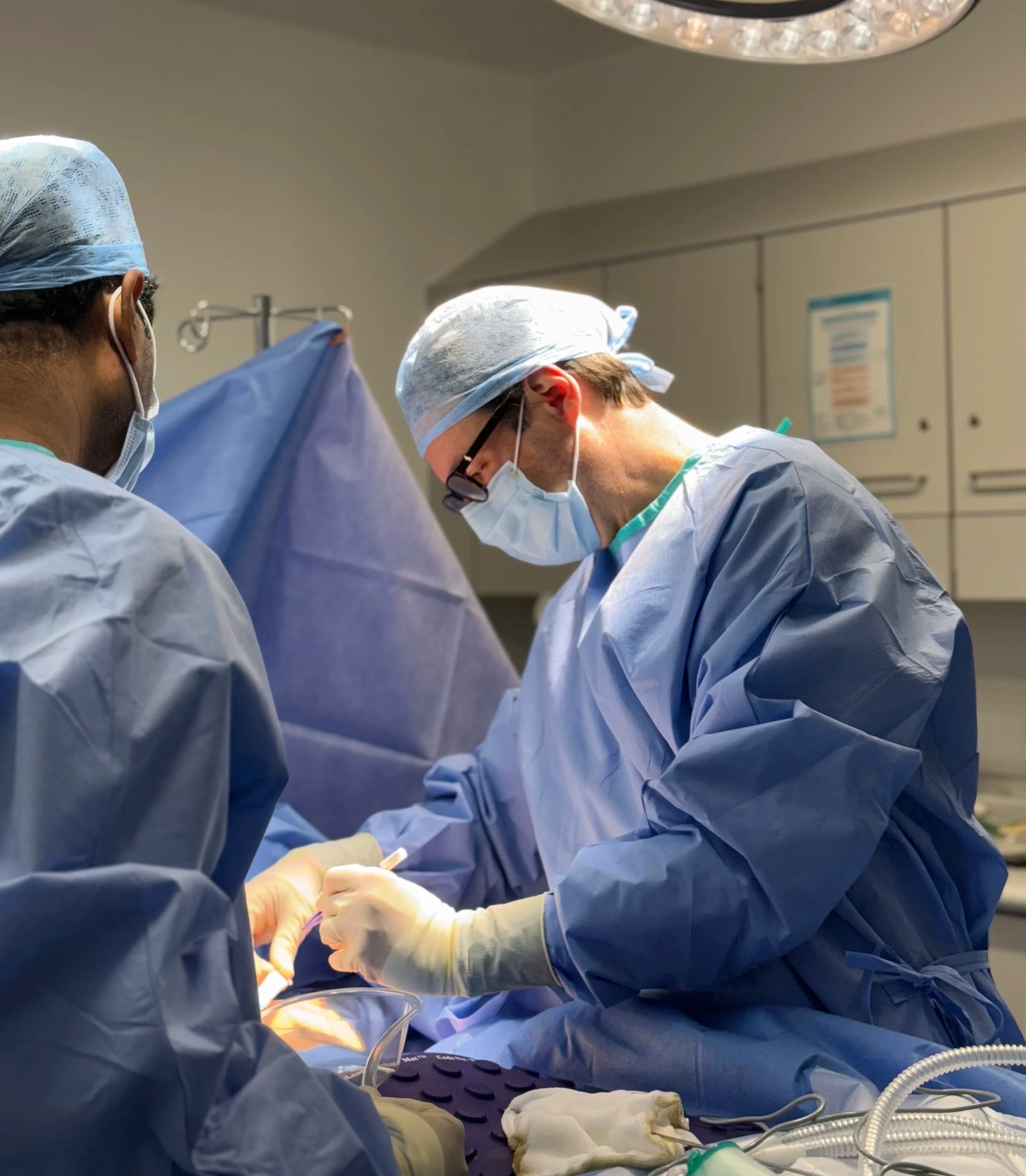 Two surgeons in scrubs and masks performing surgery in an operating room