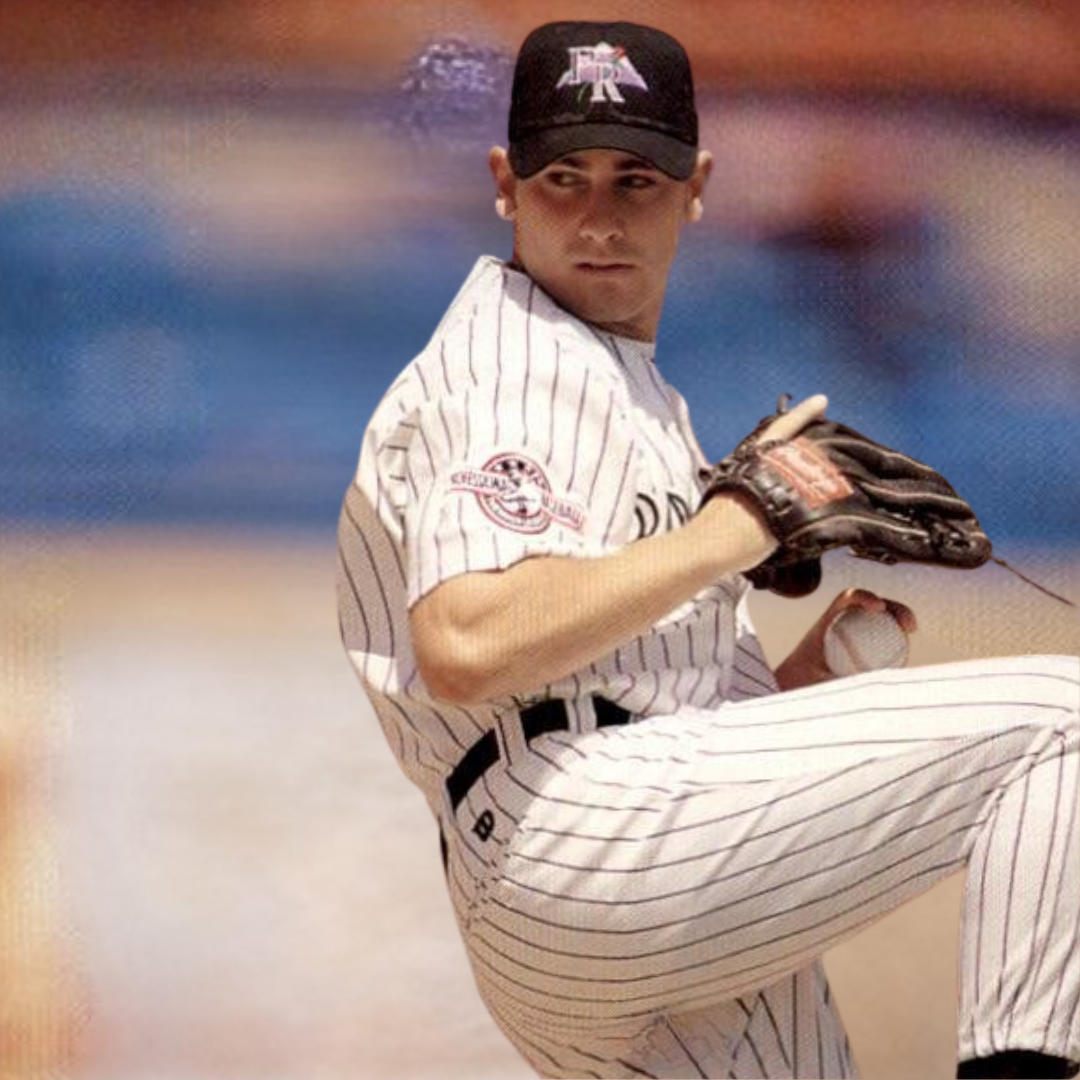 A baseball player in a pinstripe uniform holding a baseball and glove, wearing a cap, on a blurred background.