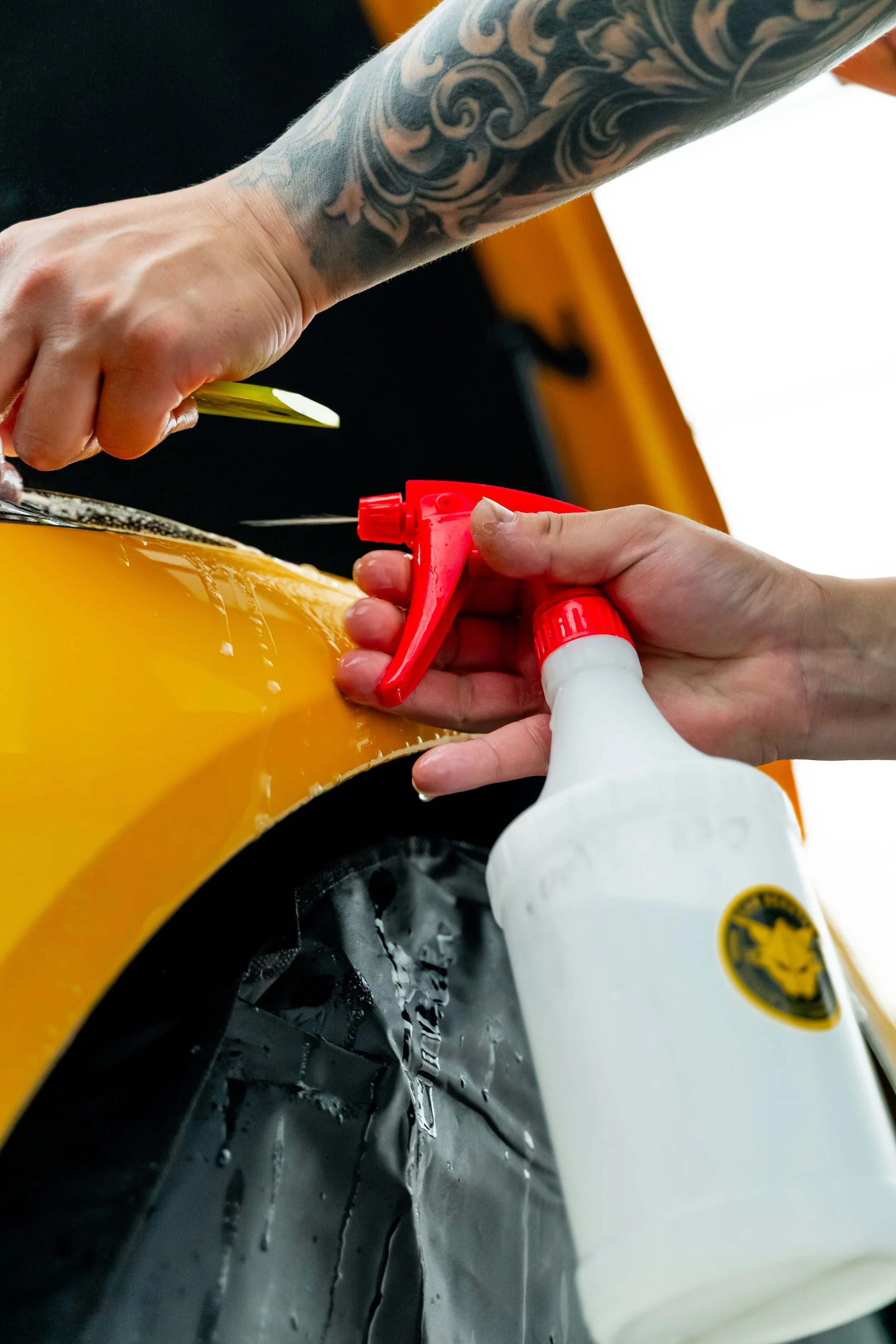 Applying ceramic coating solution to a wheel on a yellow car