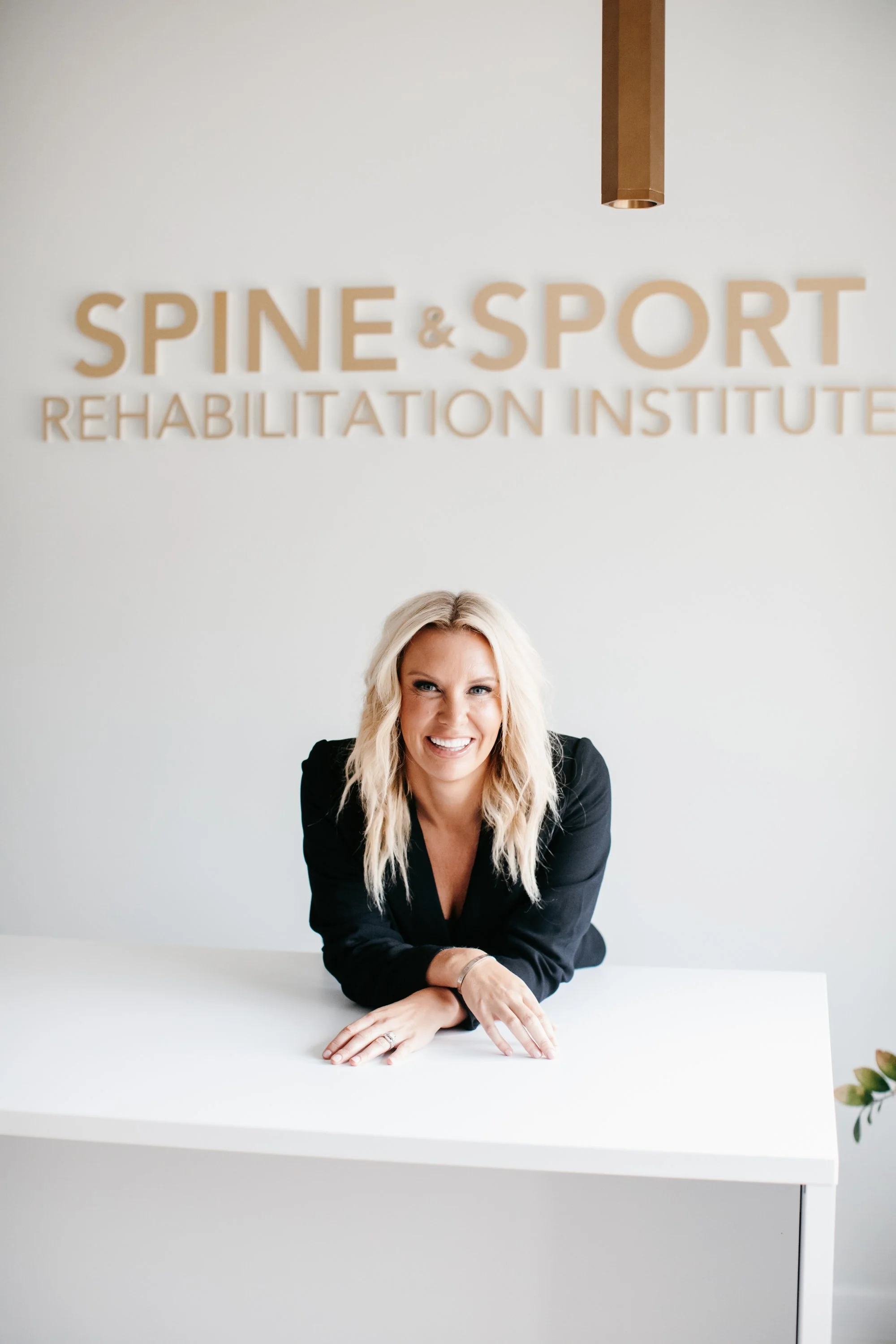 Dr. Audra Lance leaning on a white reception desk in front of a wall.