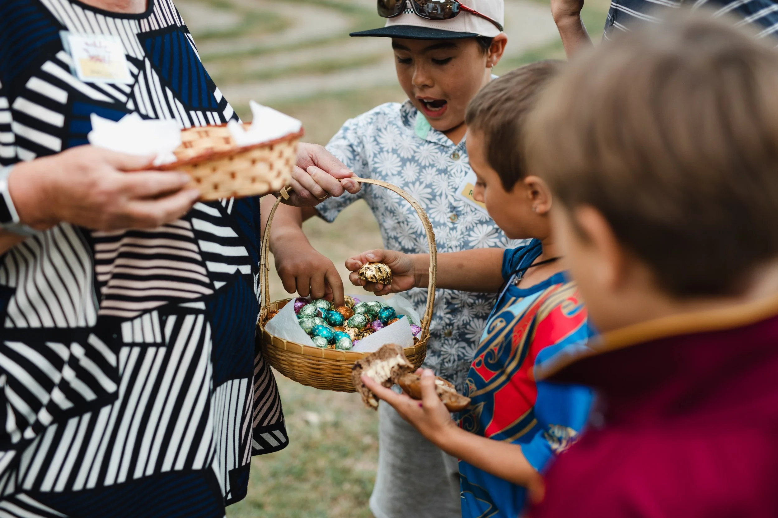 Children receiving chocolate eggs from an adult during Easter egg hunt.