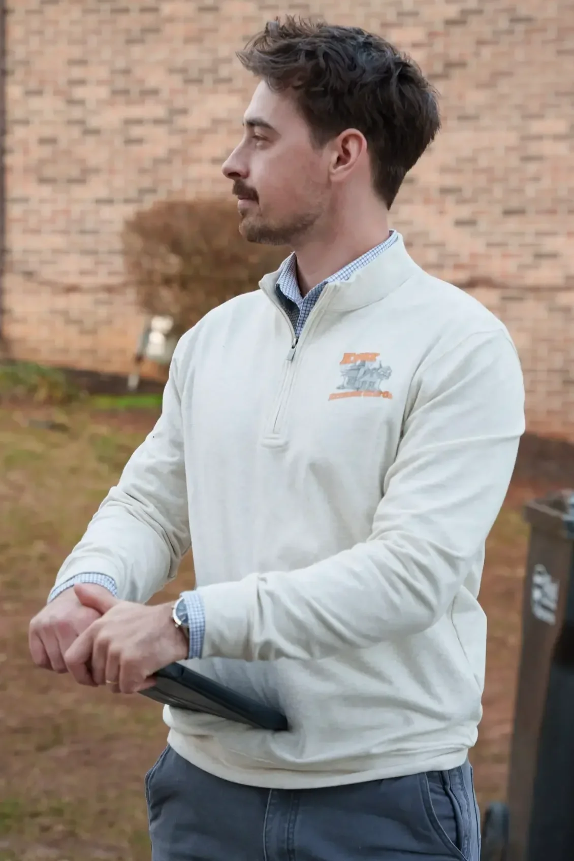 Owner of Knox Exterior Care Co., standing with an iPad, looking to his right, wearing a white branded pullover.