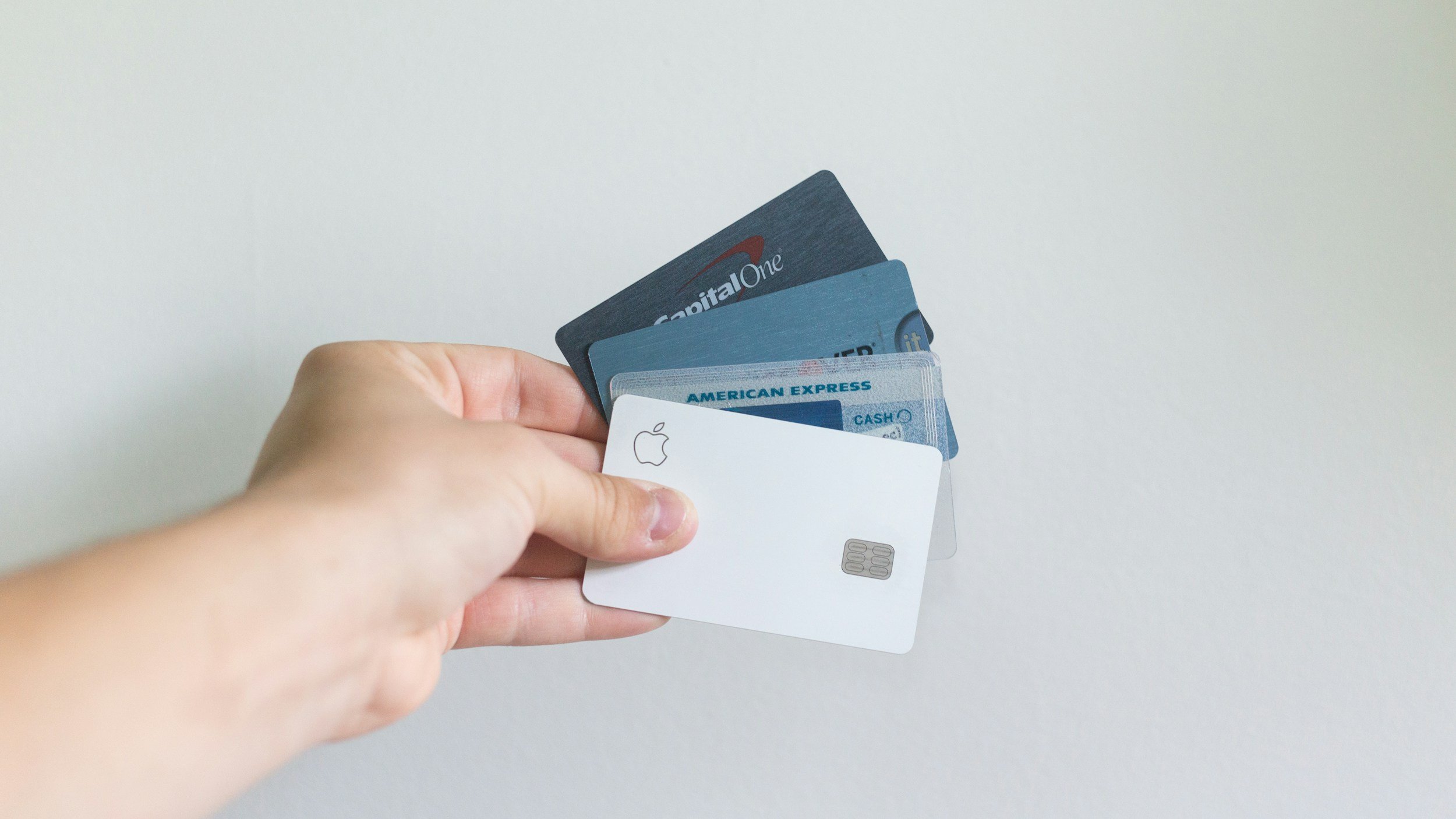 A hand holding several credit cards against a plain white background.