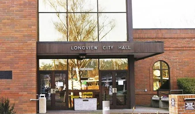 Entrance to Longview City Hall with glass doors, brick walls, and a sign above the door.