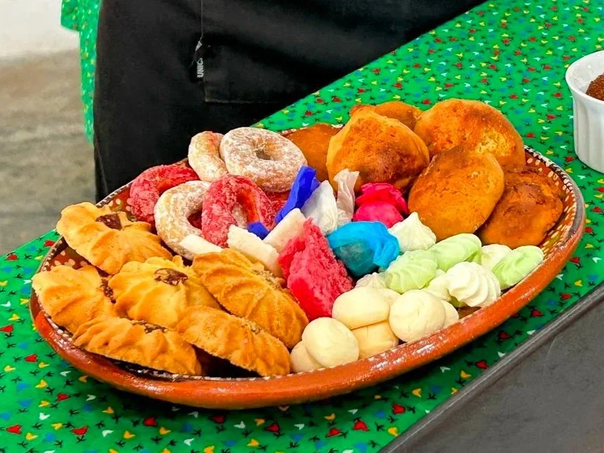 A platter of various fried foods, colorful candies, and cookies on a festive green tablecloth.
