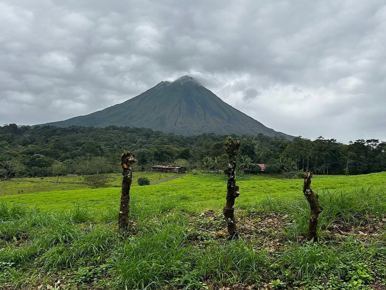 volcano arenal clouds green field costa rica