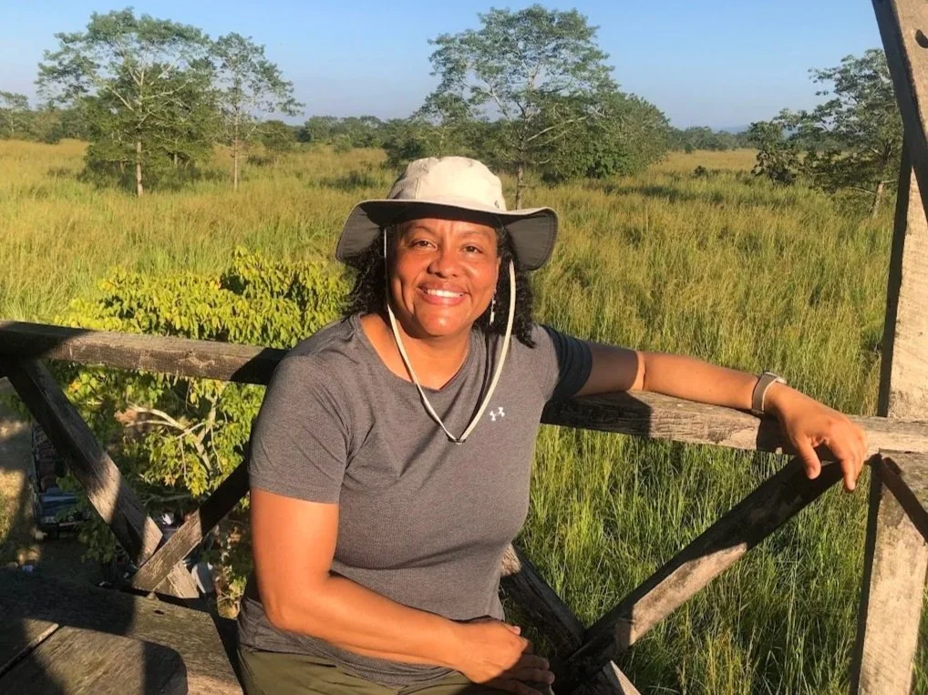 female brown women with sun hat on safari with grassy plain