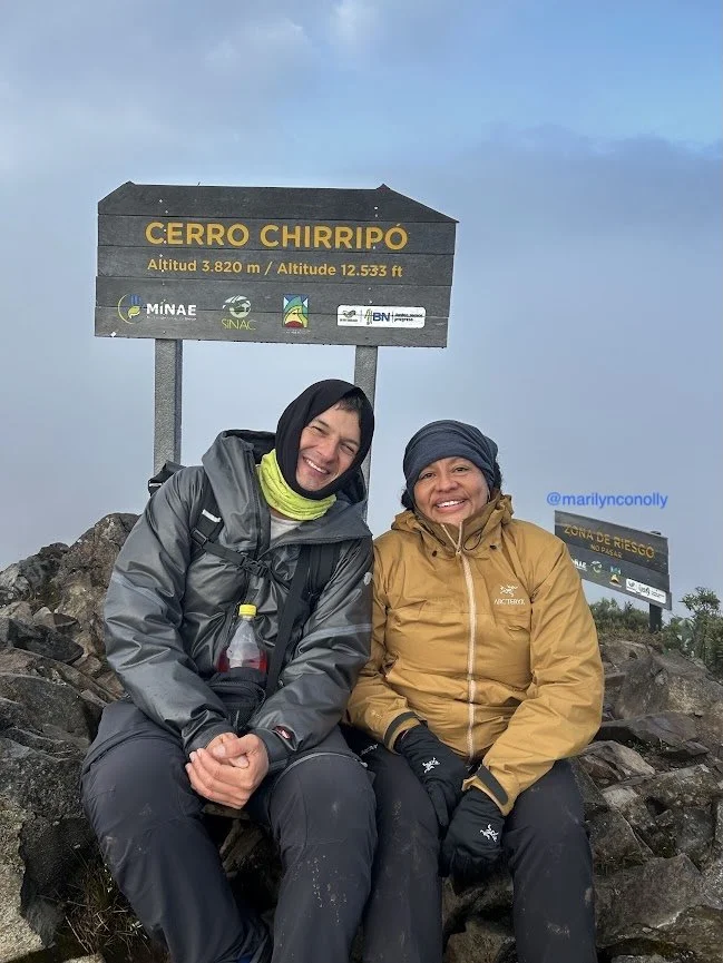 woman hiker and man guide on summit of cerro chirripo in costa rica cloudy sitting on rocky mountain top