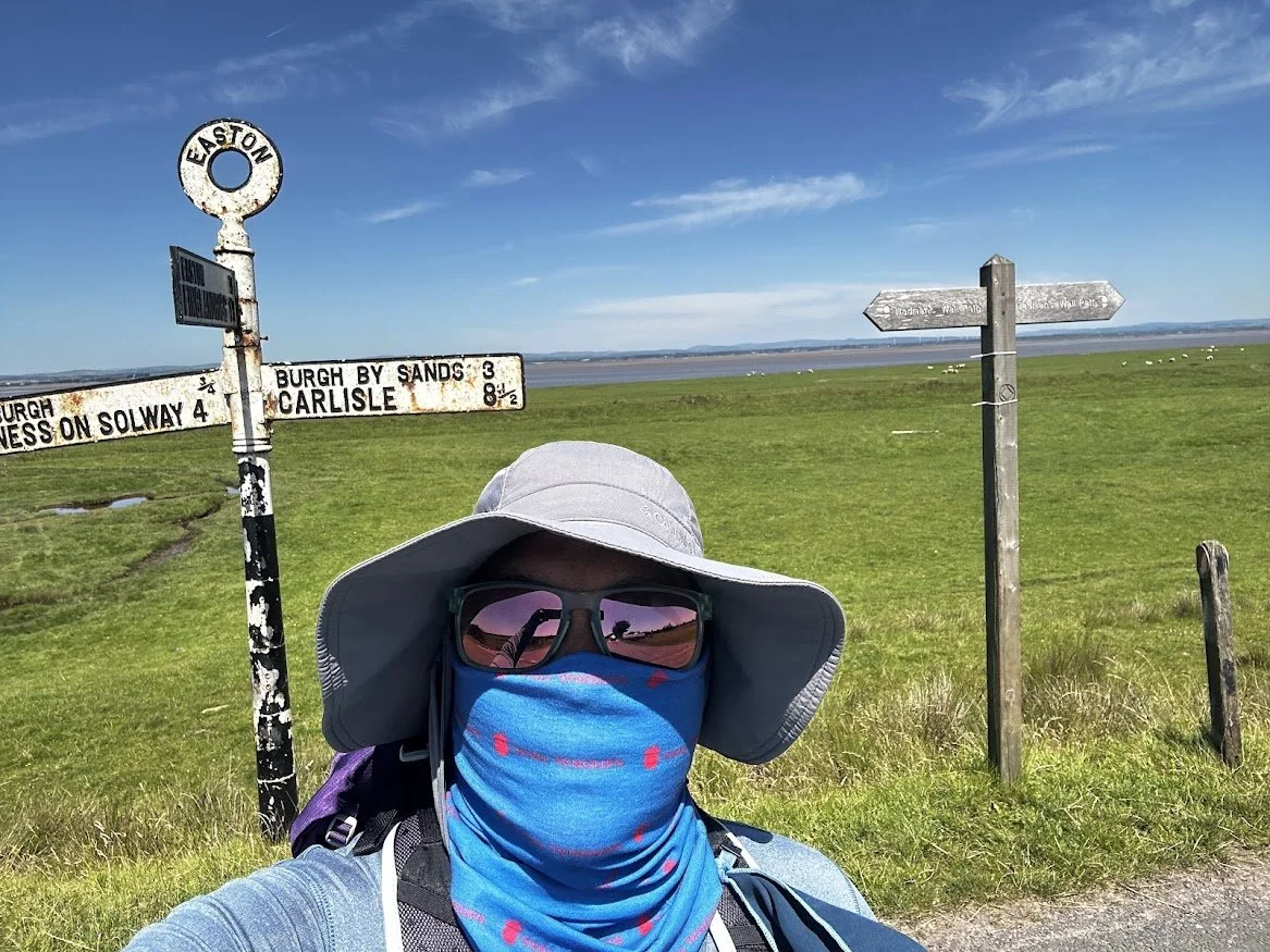 woman hiker face covered in sun on country road with city sign marker and blue skies