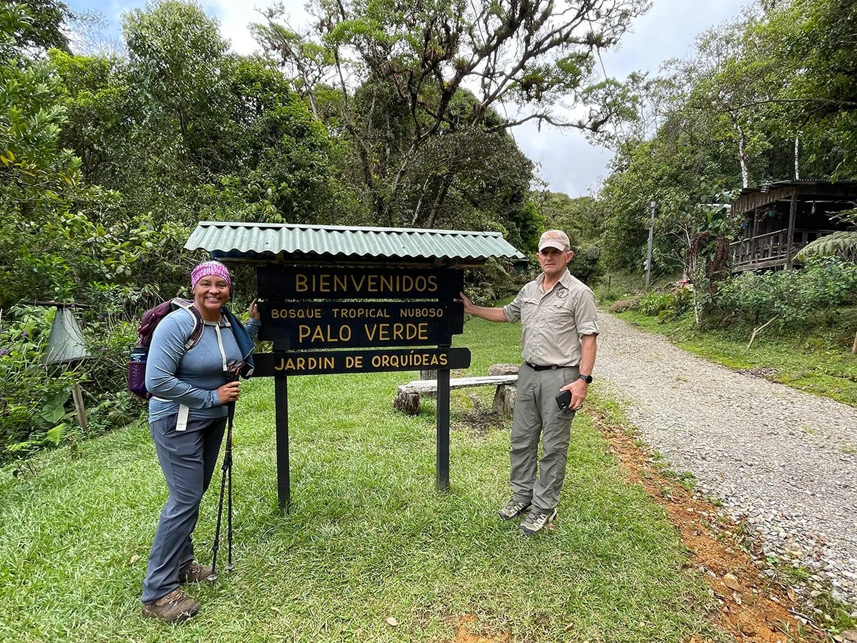 women hiker and costa rican at palo verde forest hiking poles hand on sign