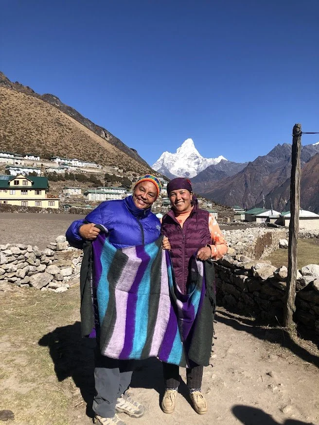 hiker woman with nepalese woman holding a wool shawl in mountains himalayas