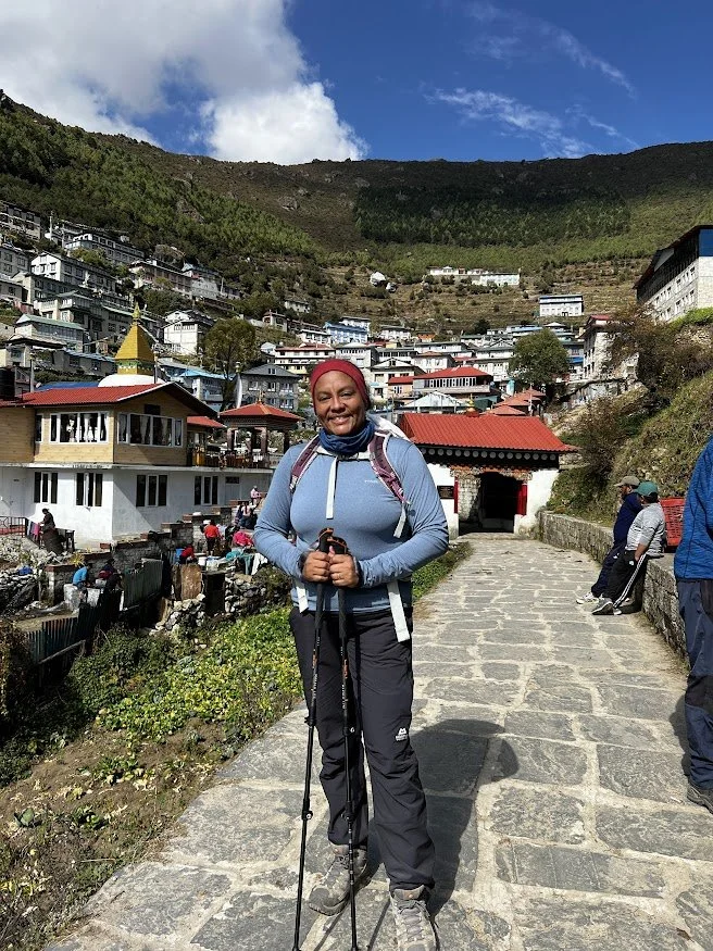 woman hiker with hiking poles in front of entrance to namche bazaar nepal