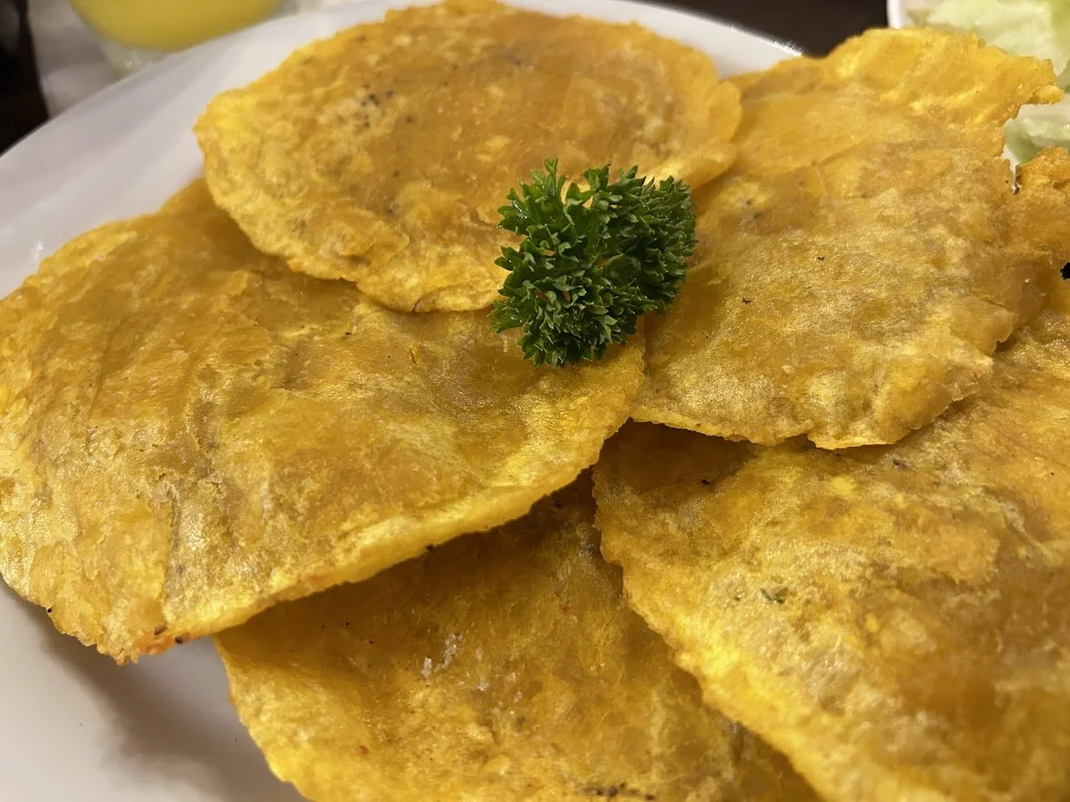Fried fish fillets garnished with a sprig of parsley on a white plate.