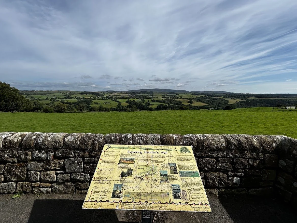 open skies landscape with a stone wall and signpost cloudy