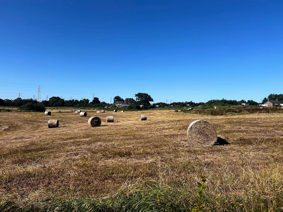 open countryside field of bales of hay with blue skies