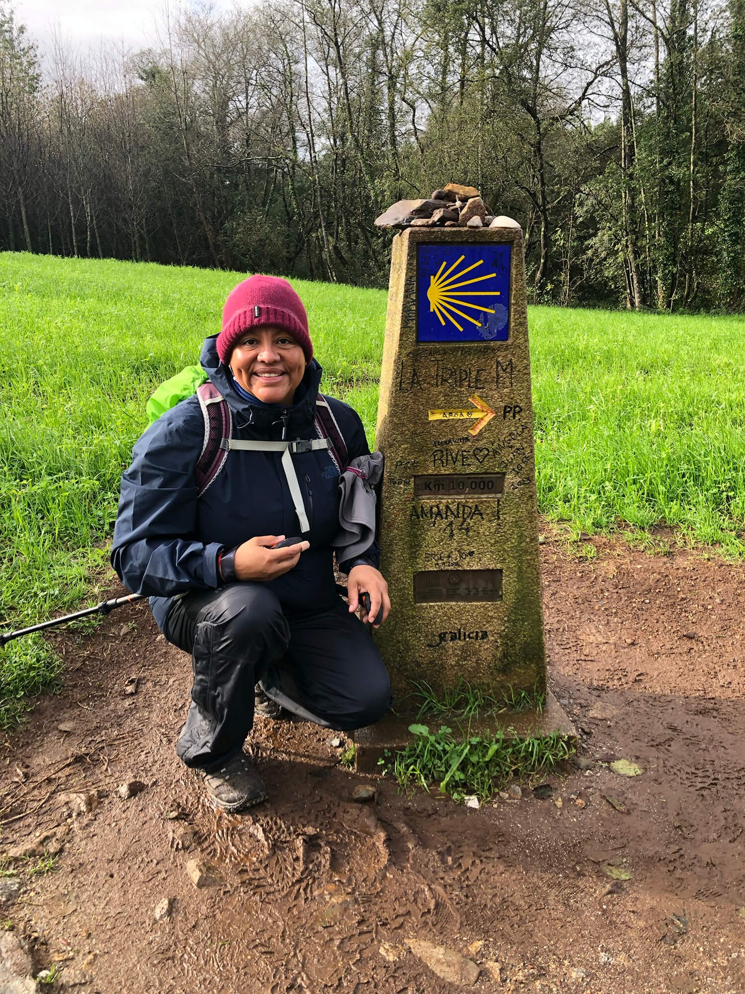 woman kneeling next to camino way marker