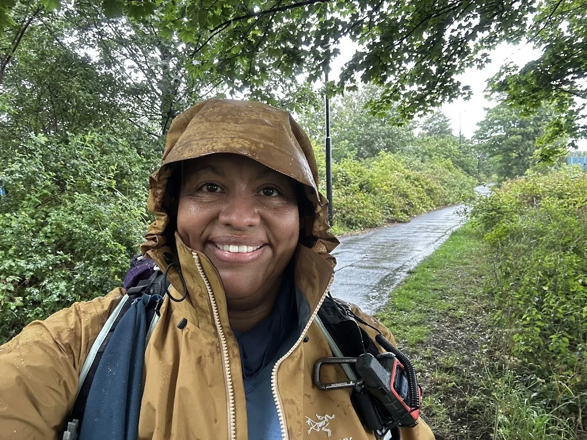 woman hiker smiling in rain jacket on countryside trail