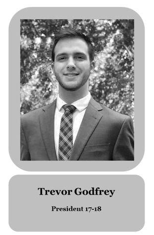 Black-and-white portrait of Trevor Godfrey, president from 2017 to 2018, wearing a suit and tie, outdoors with trees in the background.