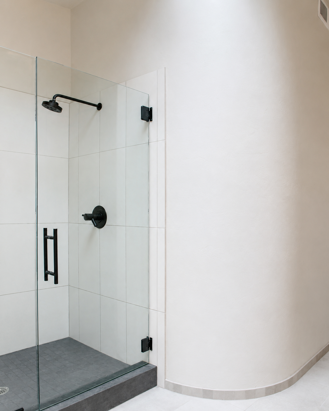 Empty glass shower enclosure with black fixtures in a modern bathroom.