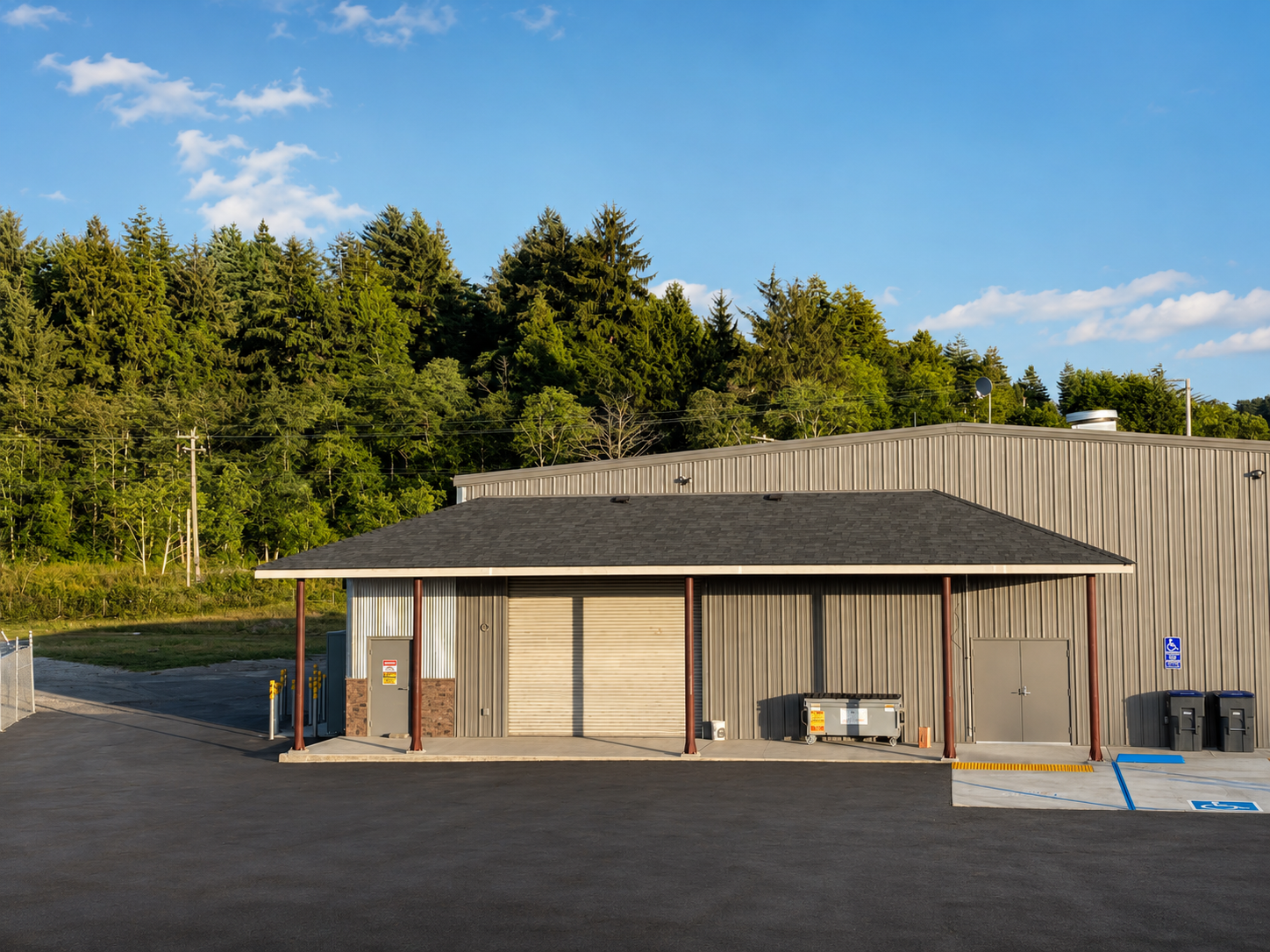 Commercial building with a metal exterior, two garage doors, and a parking lot with accessible parking designated.