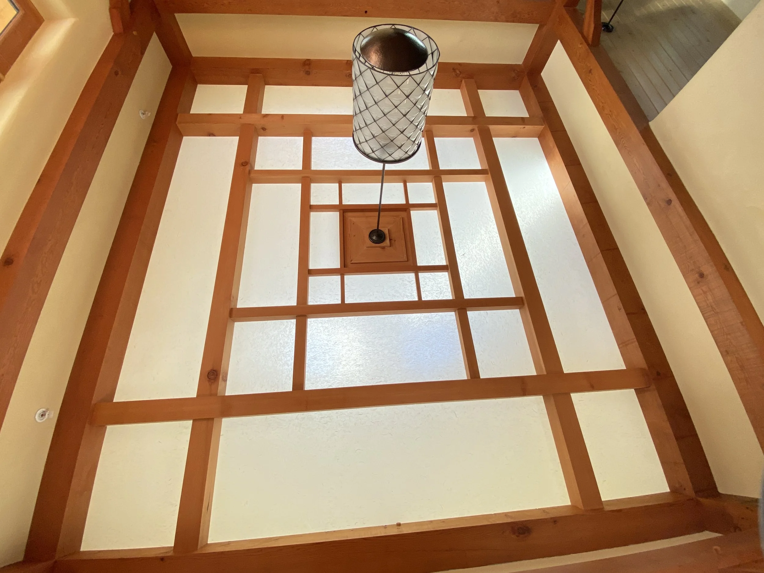 View of a ceiling with wooden framing and a hanging light fixture.