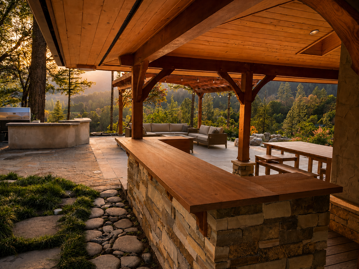 An outdoor patio area with wooden beams and furniture, overlooking a lush green forest and mountain landscape during sunset.