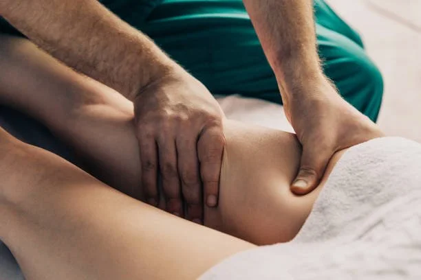 A person receiving a massage on their knee from a therapist.