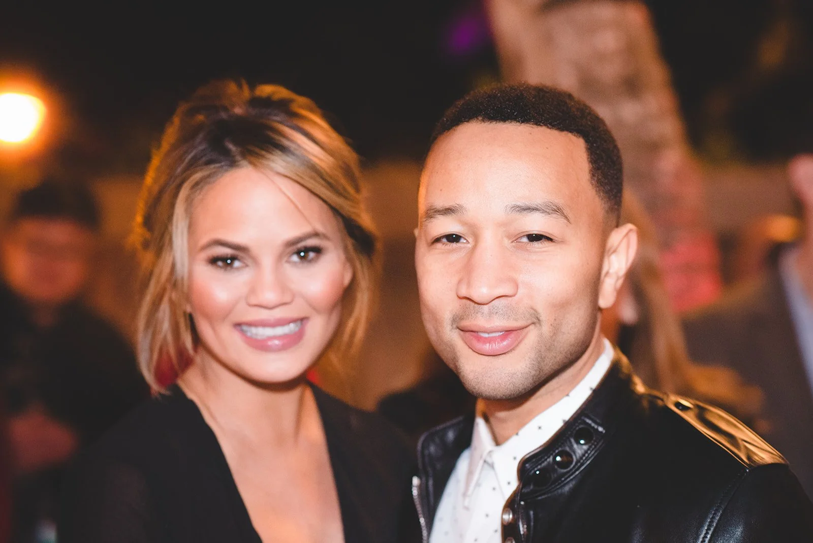 Smiling woman with shoulder-length blonde hair and a man with short black hair at a social event.