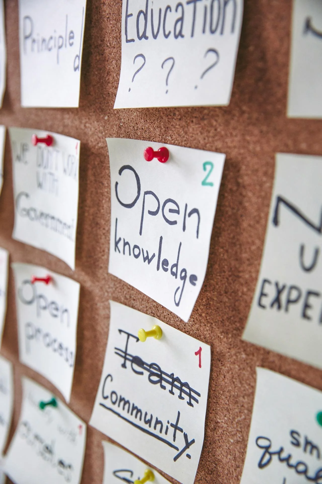 Notes pinned to a corkboard, with one note reading 'Open knowledge' and another reading 'Hear; community'.
