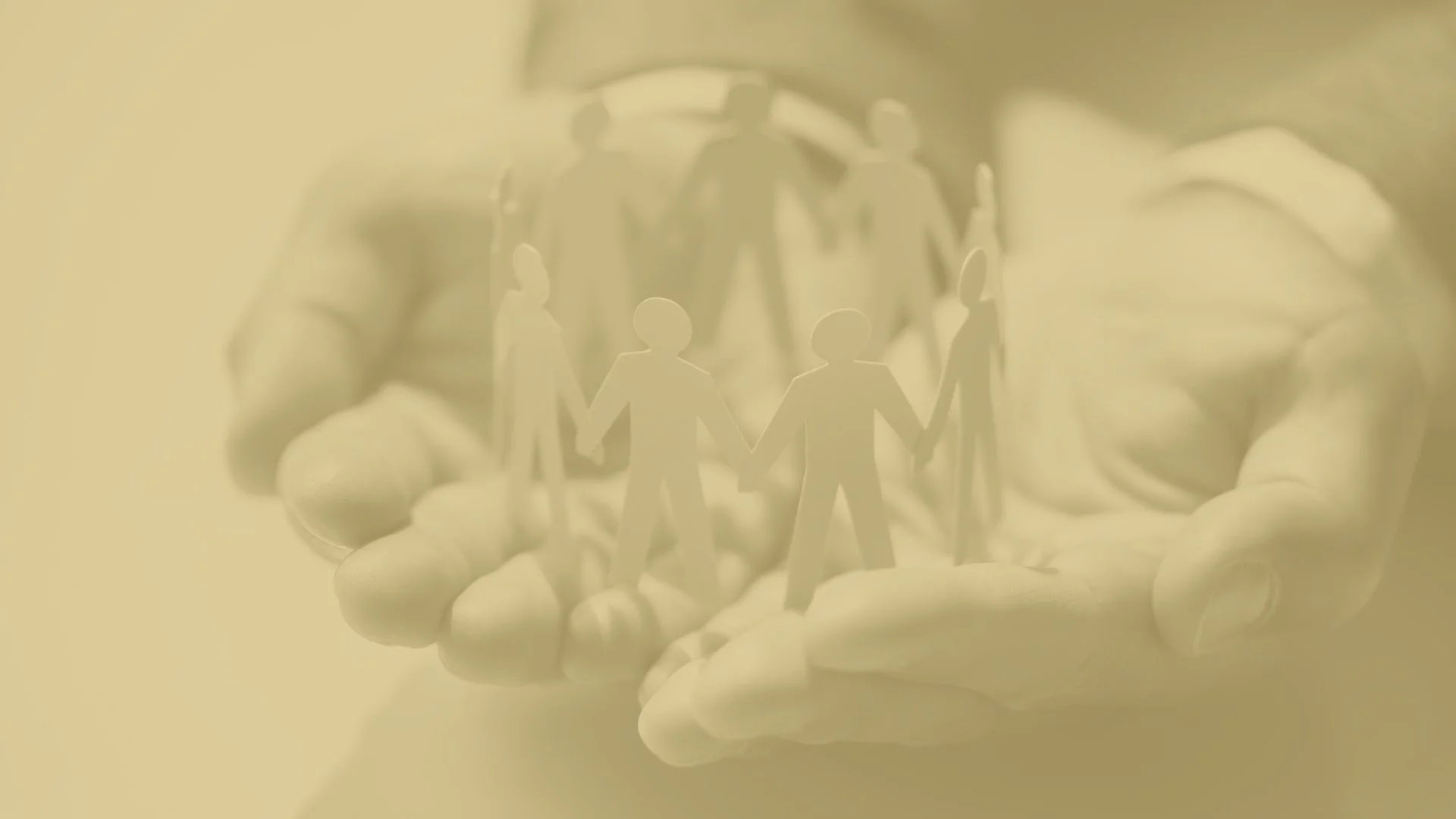 A pair of hands holding a paper cutout of people holding hands, symbolizing community or unity.