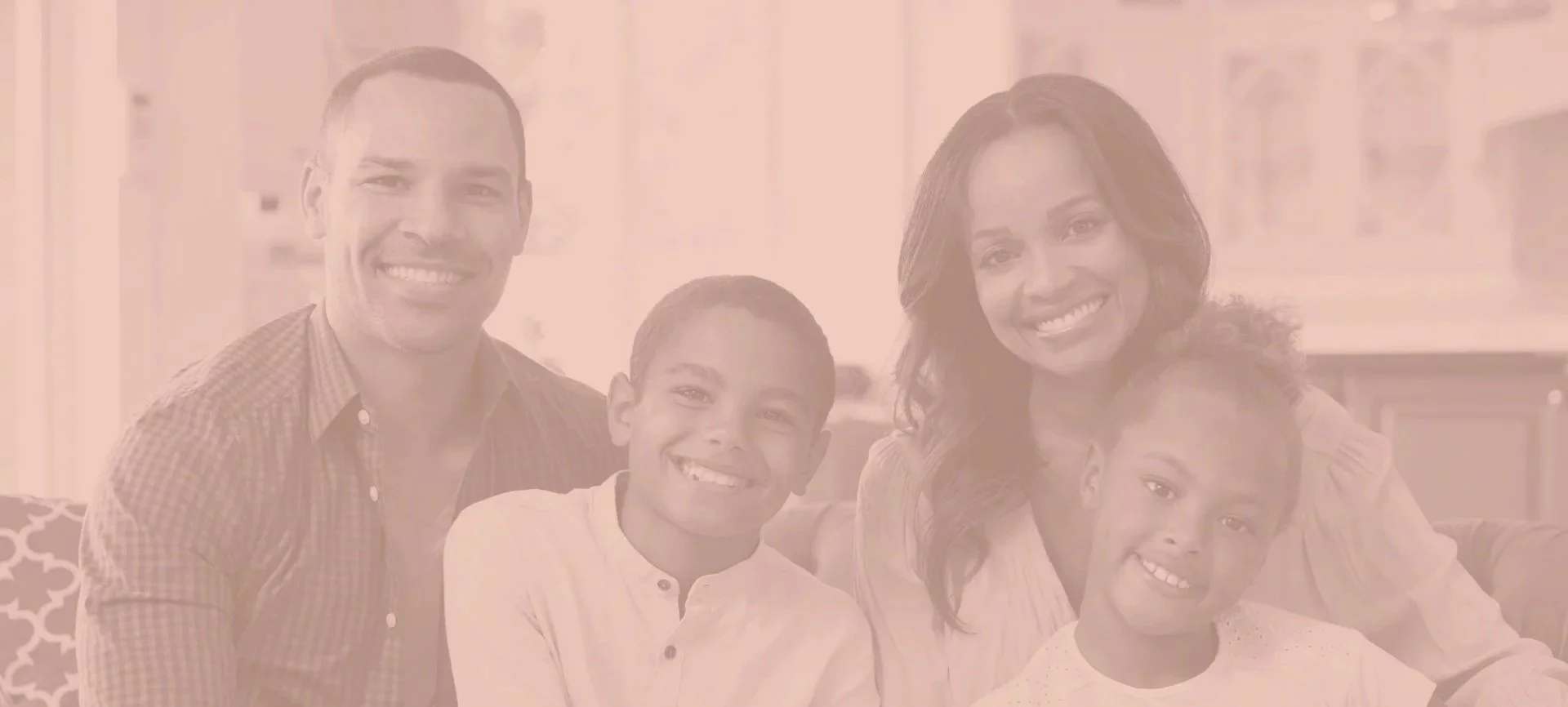 A happy multiracial family of four posing together in a home interior, smiling at the camera.