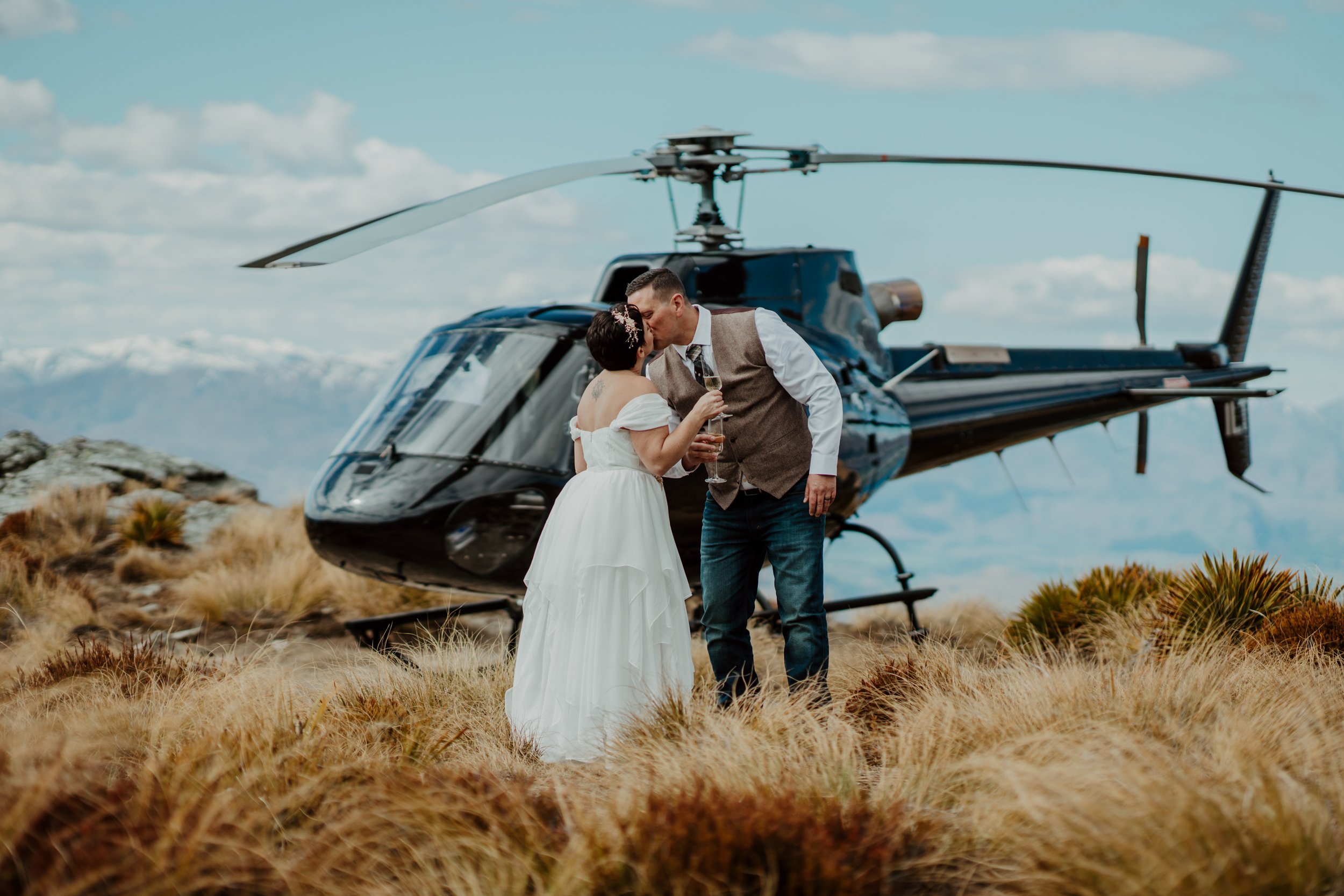 Couple standing in front of a helicopter at Cecil Peak during their Queenstown heli elopement.