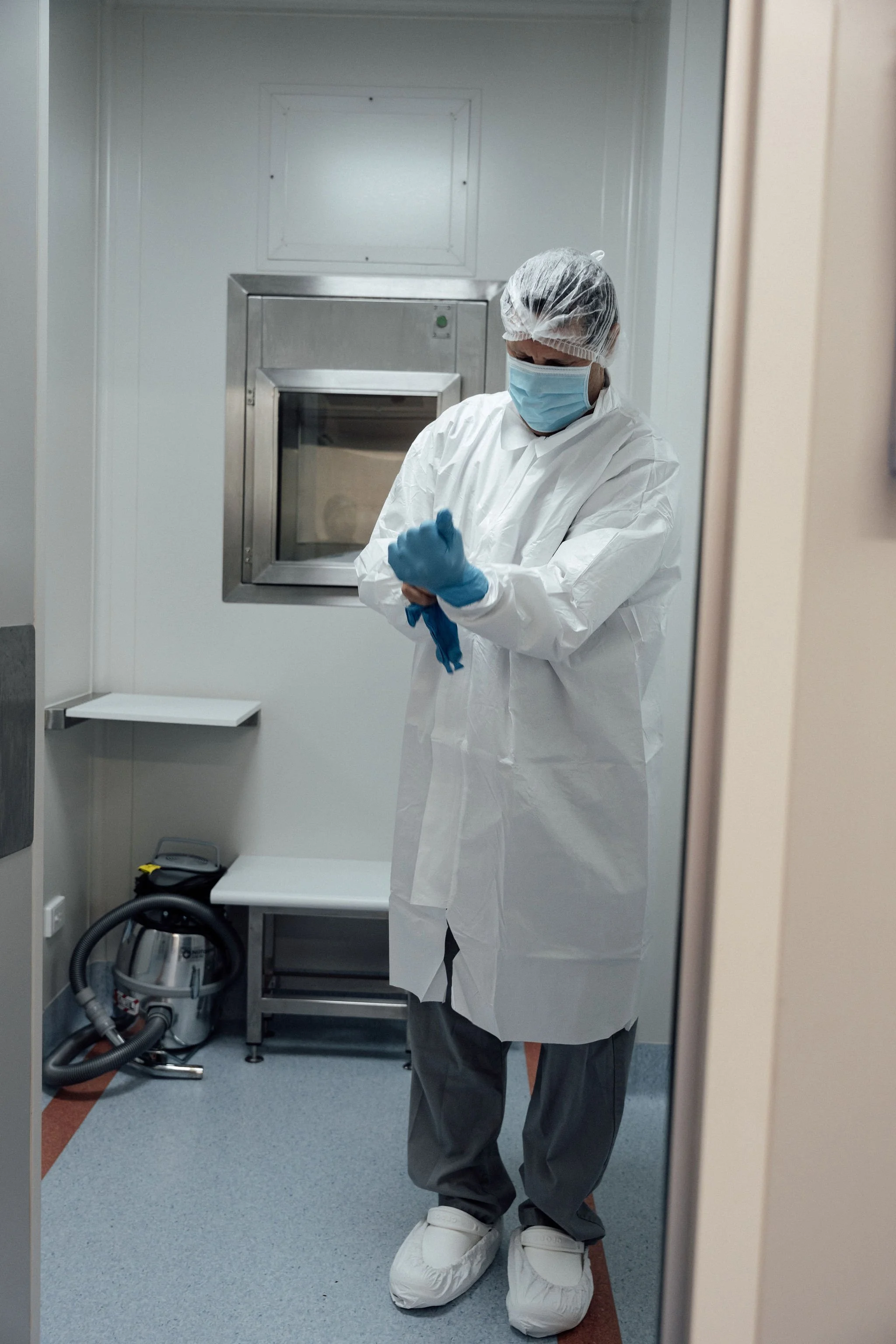 Laboratory technician in full sterile protective gear working in a controlled cleanroom environment