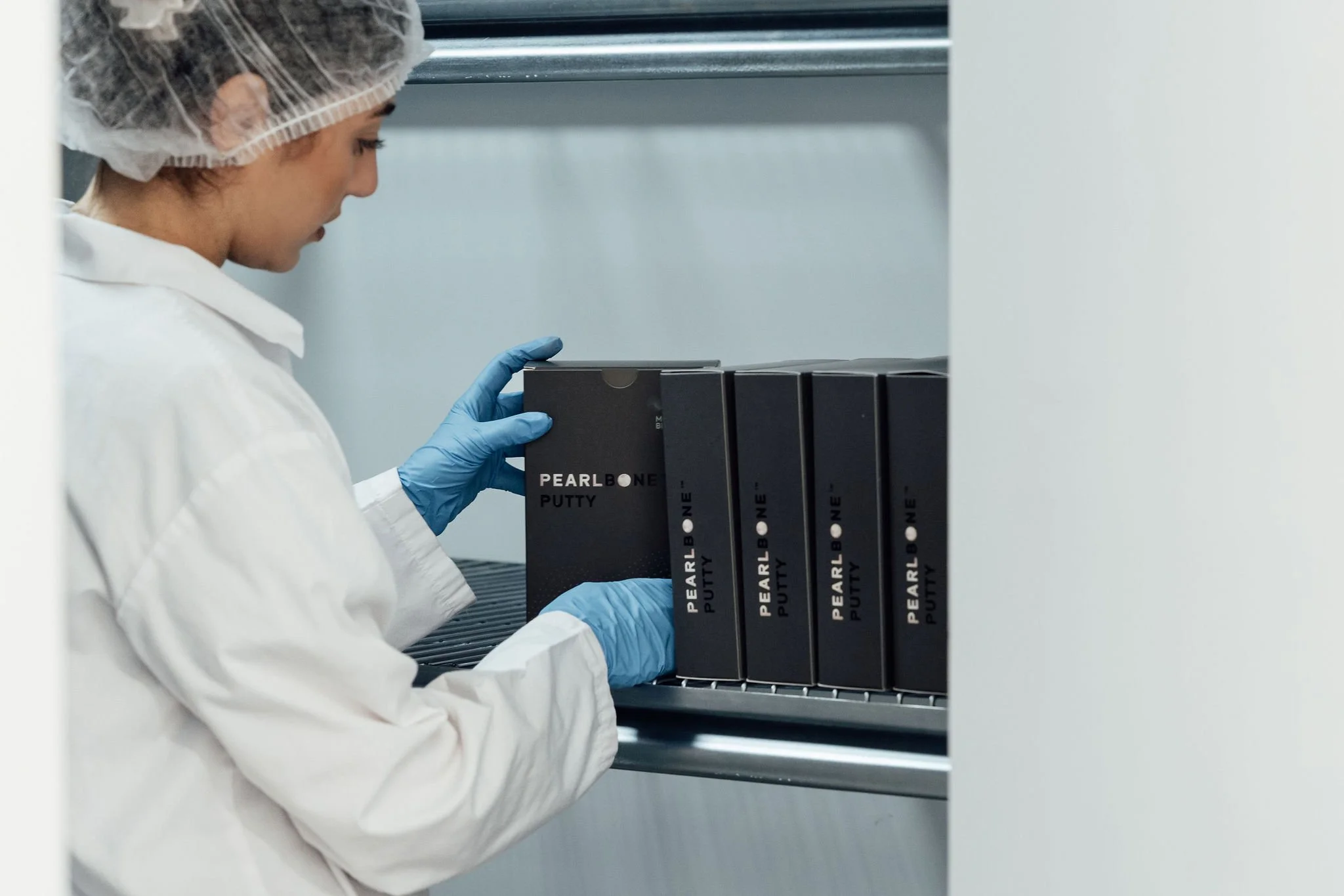 Laboratory technician handling PearlBone™ biomaterial packaging in a controlled lab environment