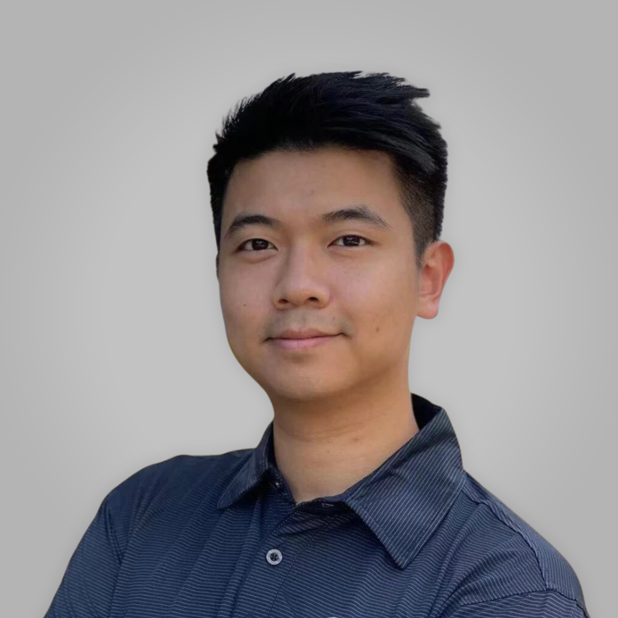 Partial portrait of an Asian man with black hair, wearing a navy blue striped shirt, against a neutral gray background.