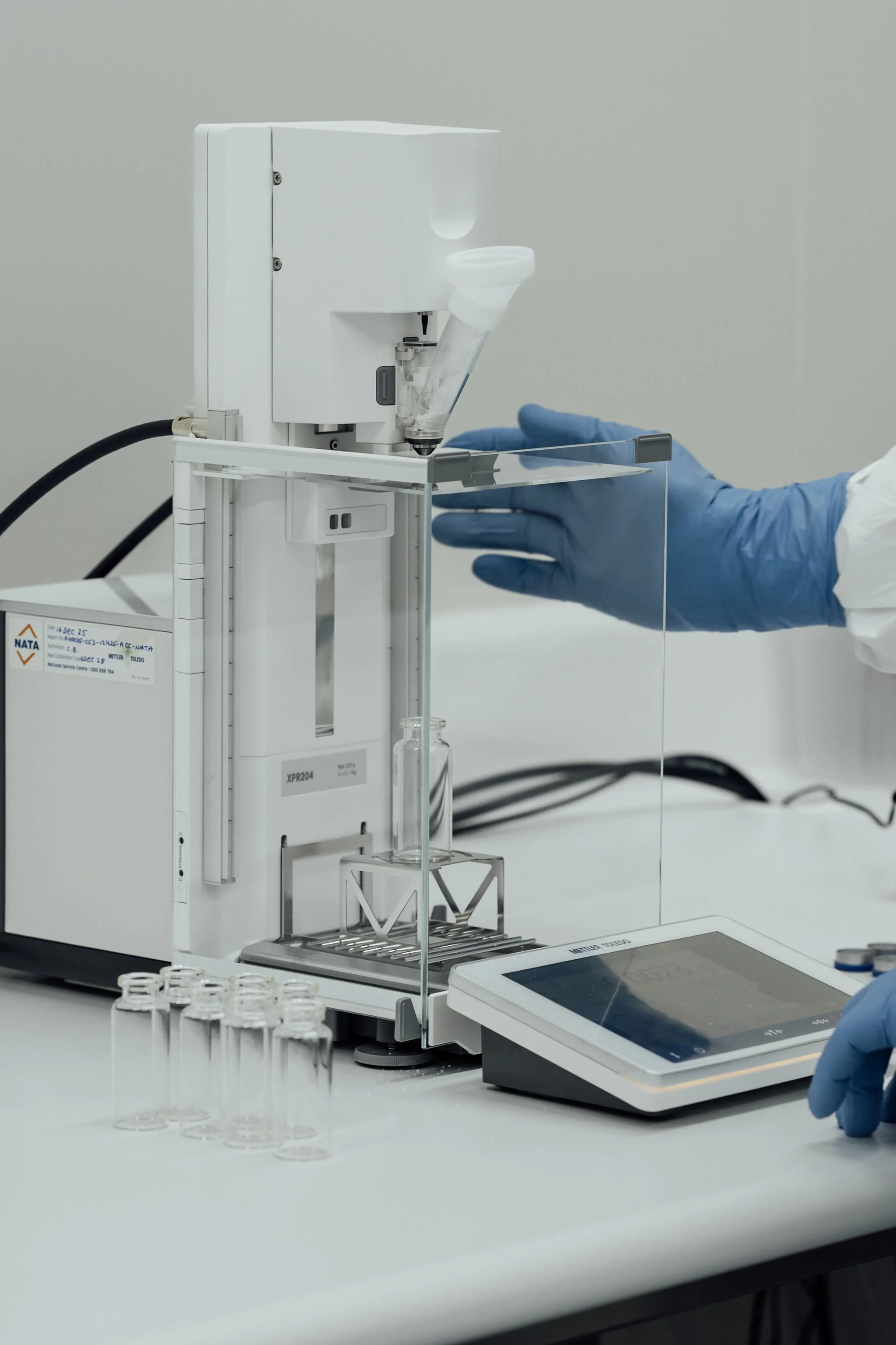 Laboratory technician operating analytical equipment with glassware and measurement tools on a lab bench
