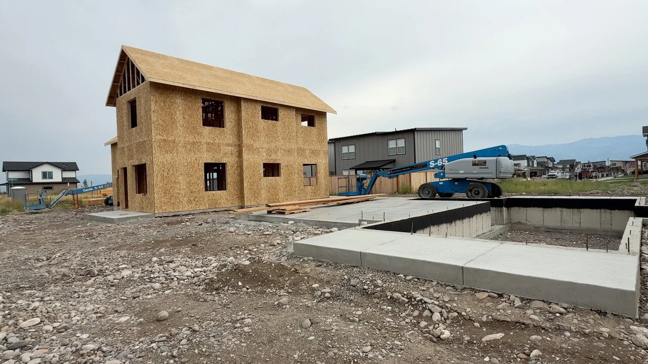 the frame of a home on a plot in a neighborhood.