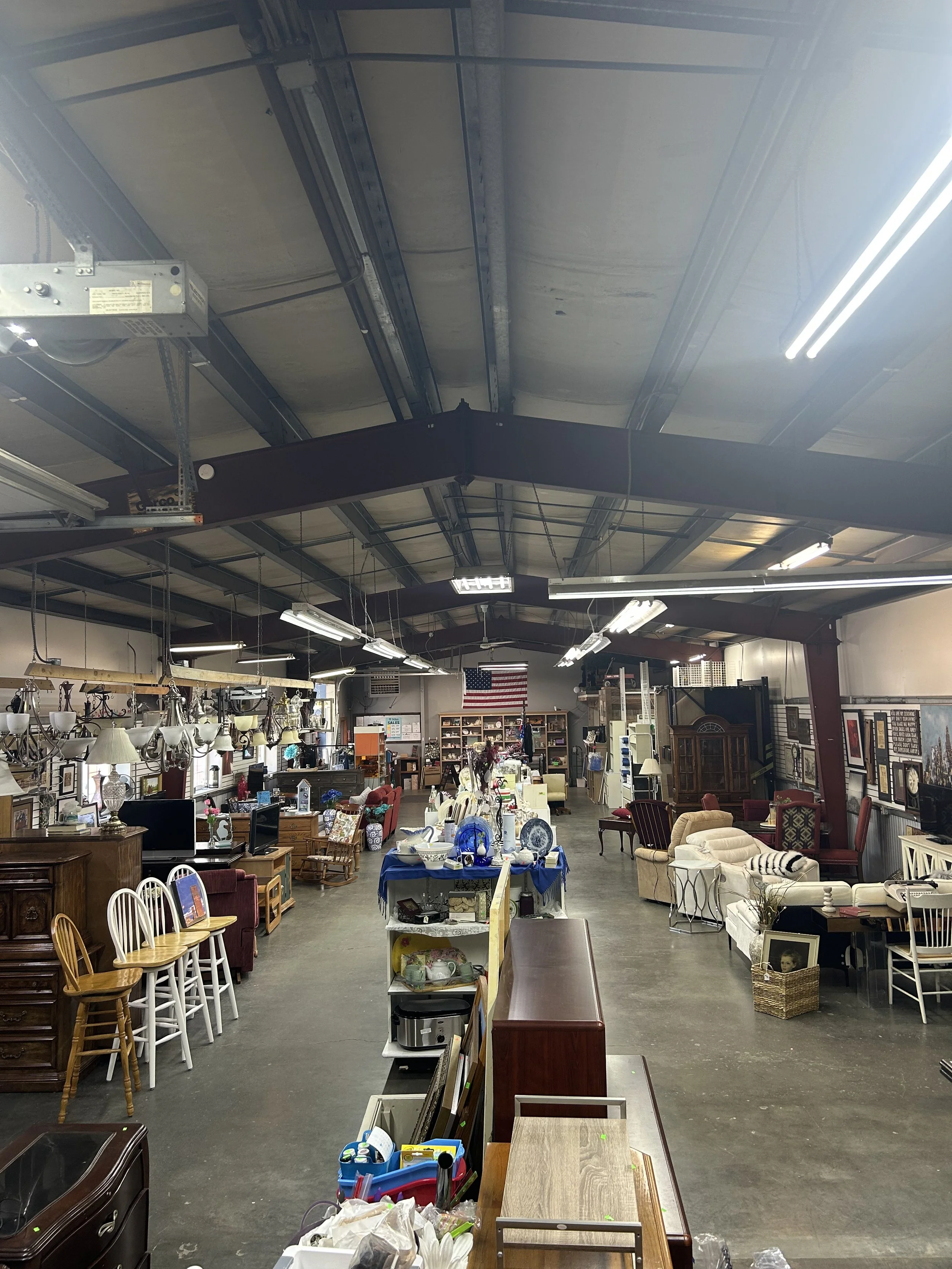 Up high view of the ReStore's main floor space. Furniture is out for sale on either sides of the room with smaller decor and kitchen wares on shelves down the middle of the store.