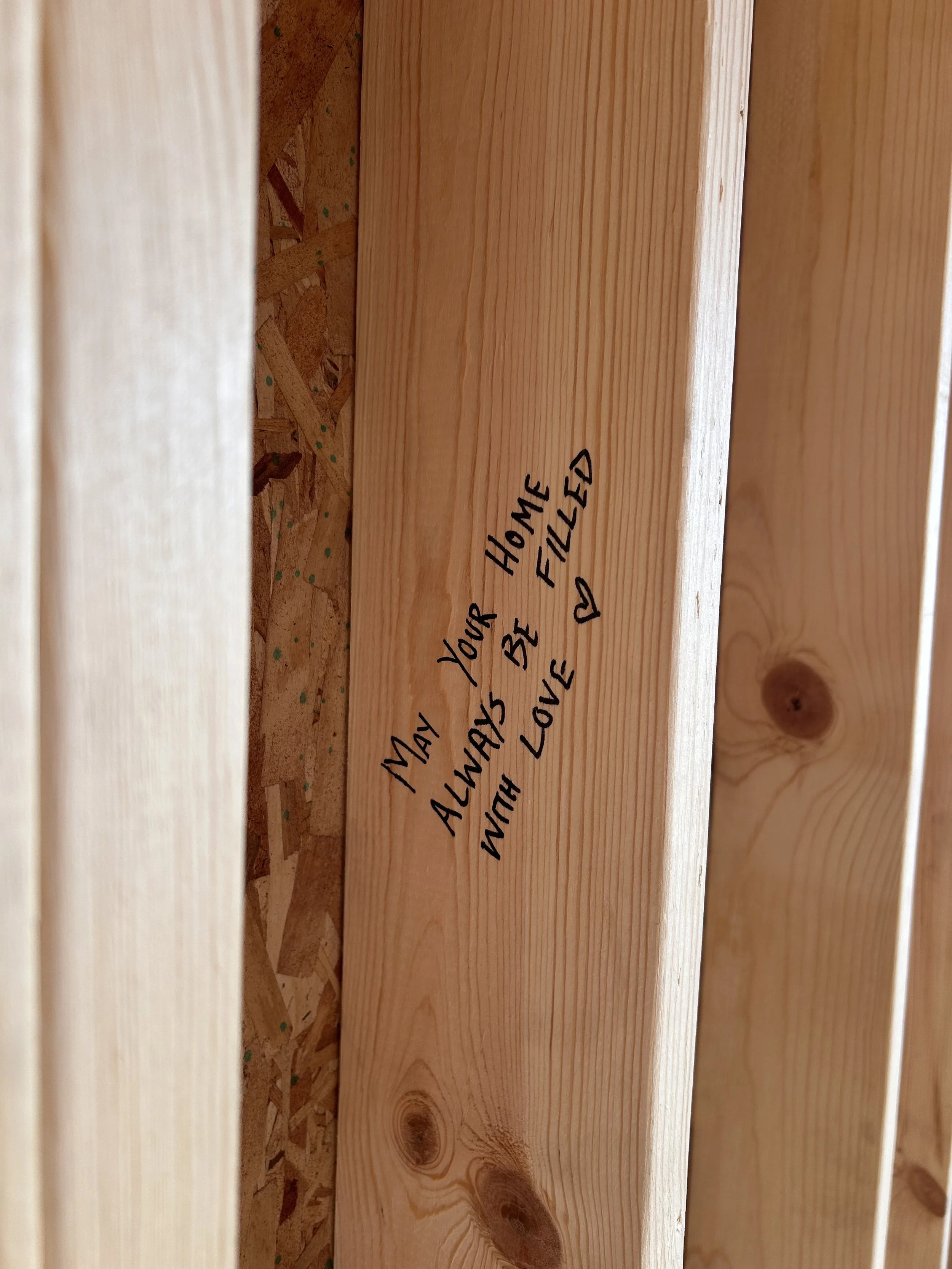 "May your home always be filled with love" written on a wooden beam of the framing of the house.