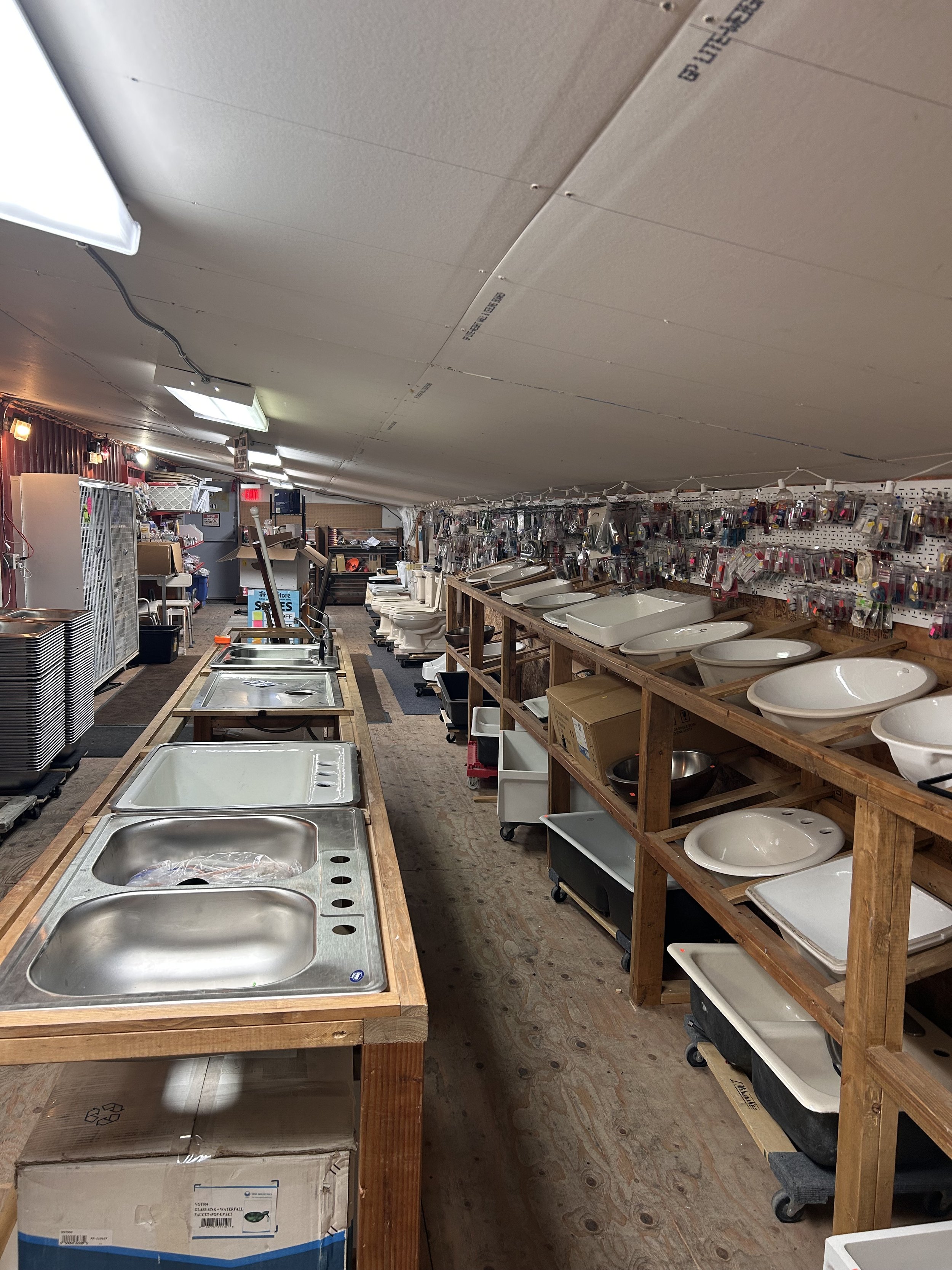 The ReStore's plumbing room featuring shelves of sinks, a row of toilets, and other plumbing hardware organized for sale.
