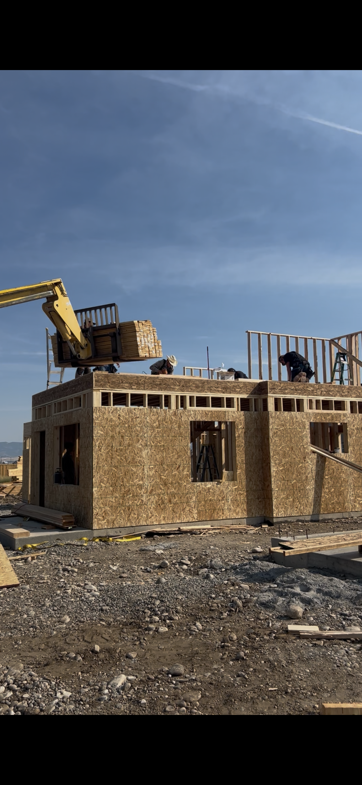 Second floor house framing. Workers present with lumber being delivered to the second floor by construction lift.