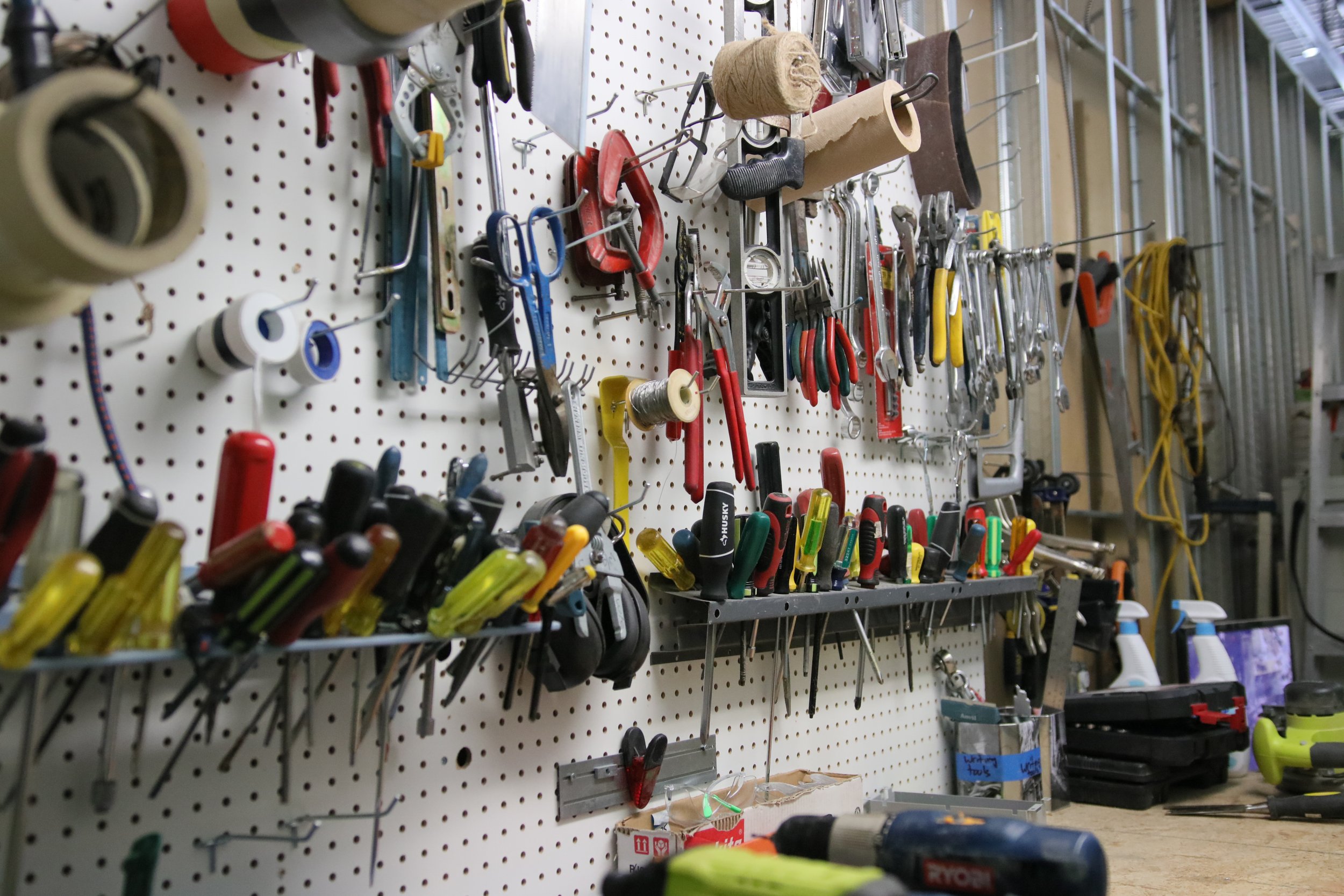 Peg board wall with various hand tools hanging.