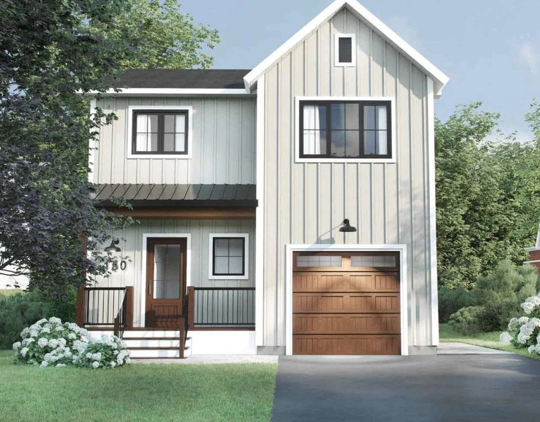 A two-story white house with vertical siding, black window frames, and a wooden garage door, surrounded by green trees and bushes, with front steps leading to the door.