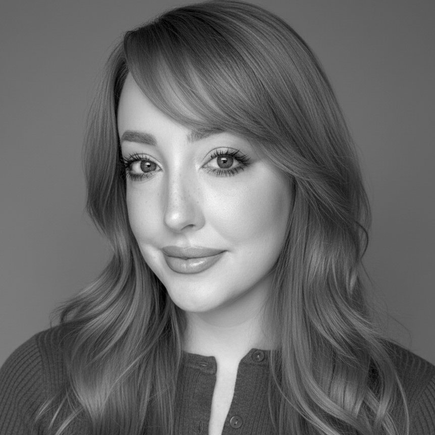 Black and white portrait of a young woman with long wavy hair, looking at the camera with a slight smile, wearing a buttoned top.