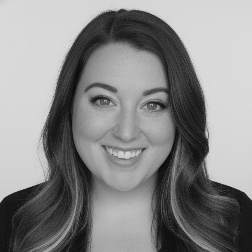 A young woman with long, wavy dark hair, smiling at the camera, in black and white.