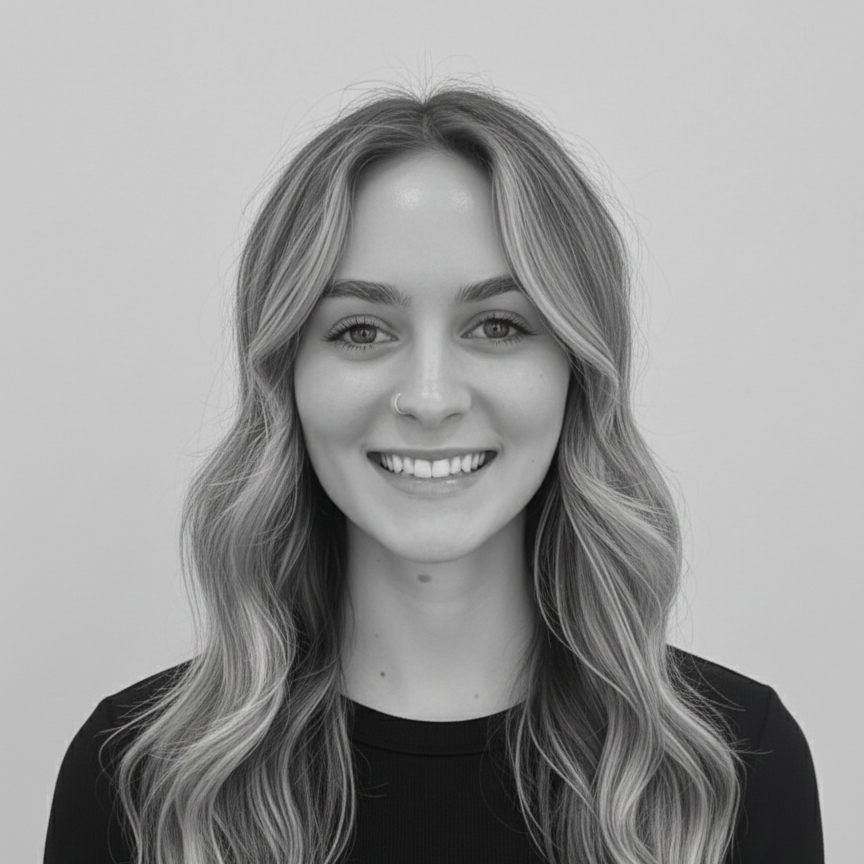 Black and white portrait of a young woman with wavy hair, smiling, wearing a nose ring and a dark top.