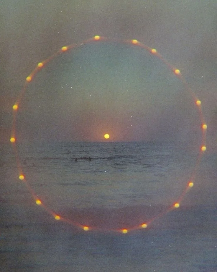 Sunset over the ocean with a circular light or lens flare effect.