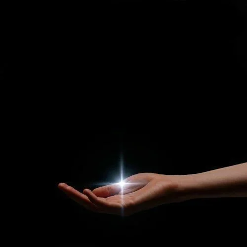 A person's hand is extended with a bright light glowing above their palm against a dark background.