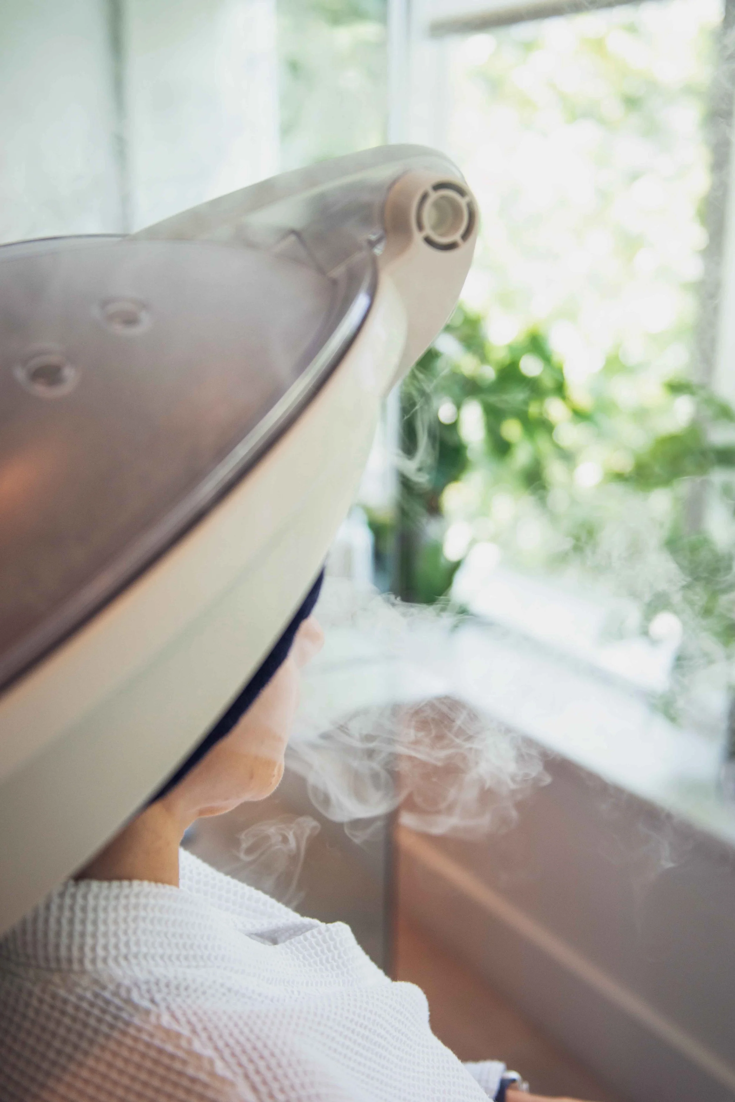 Person receiving a Micro Mist in a hair salon with plants nearby.